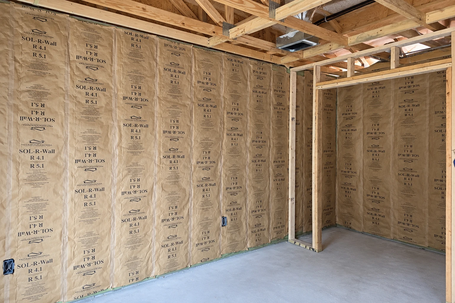 Unfinished commercial space with kraft-faced insulation fitted between exposed wall studs.