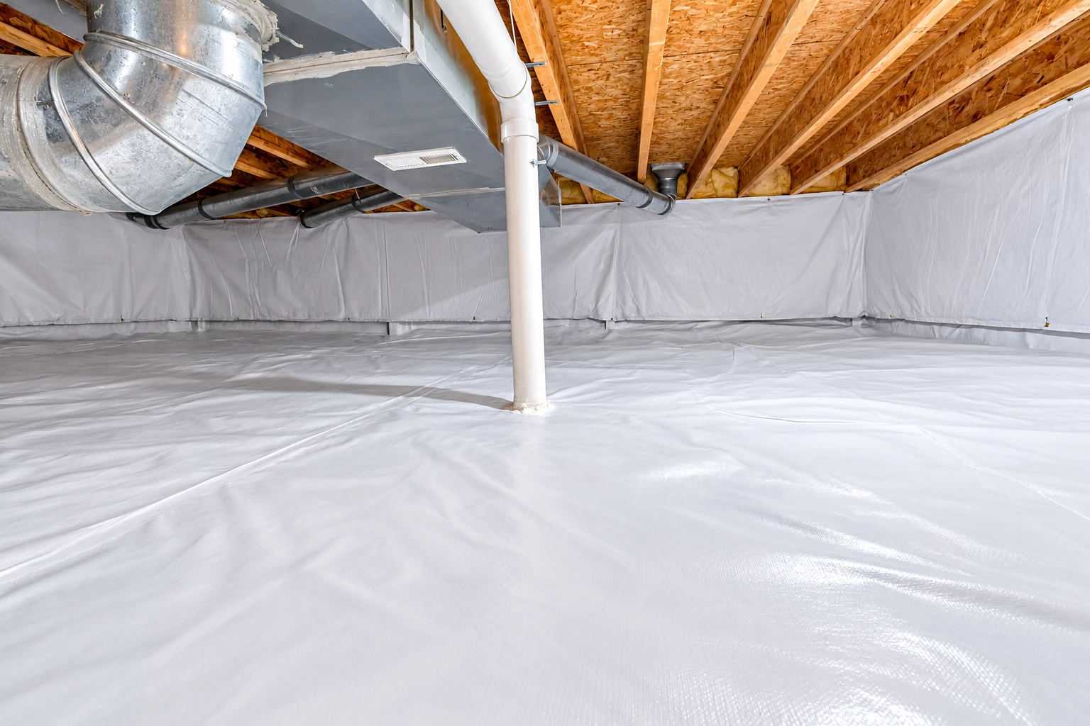 A crawl space has a white vapor barrier covering the floor and lower walls around a support pipe and ductwork.